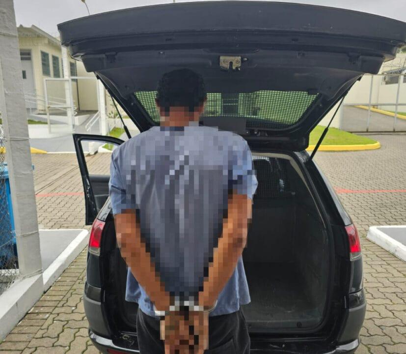Homem algemado sendo detido por policiais