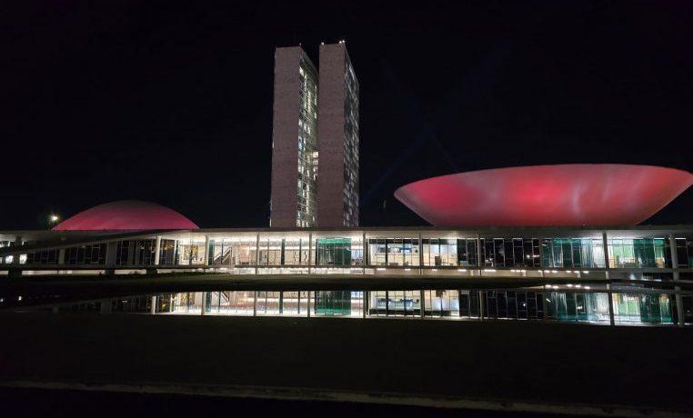 Fachada do Congresso Nacional iluminada em tonalidade bordô