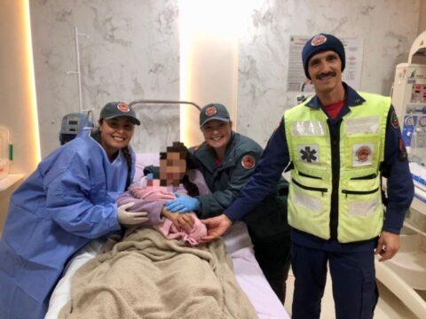 Bebê recém-nascido sendo segurado por bombeiros dentro de ambulância