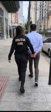 Homem algemado sendo preso por policiais