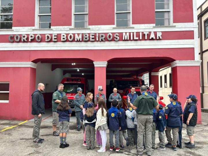 Crianças vestindo Equipamentos de Proteção Individual durante visita ao Corpo de Bombeiros