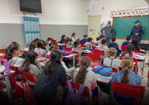 Grupo de alunos aprendendo sobre prevenção e segurança com os bombeiros
