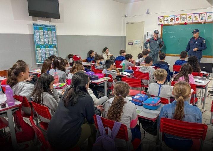 Grupo de alunos aprendendo sobre prevenção e segurança com os bombeiros