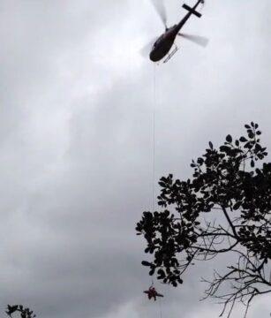 Mulher sendo resgatada em helicóptero após queda em cachoeira