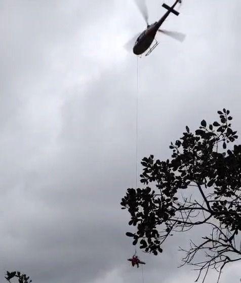 Mulher sendo resgatada em helicóptero após queda em cachoeira