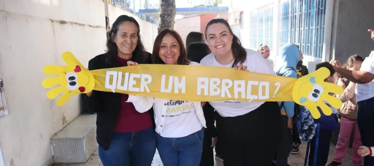 Alunos abraçados com mensagens das famílias