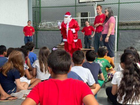 Crianças felizes recebendo brinquedos dos bombeiros e do Papai Noel