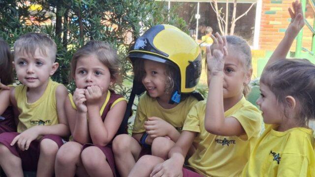 Crianças interagindo com bombeiros durante visita educativa